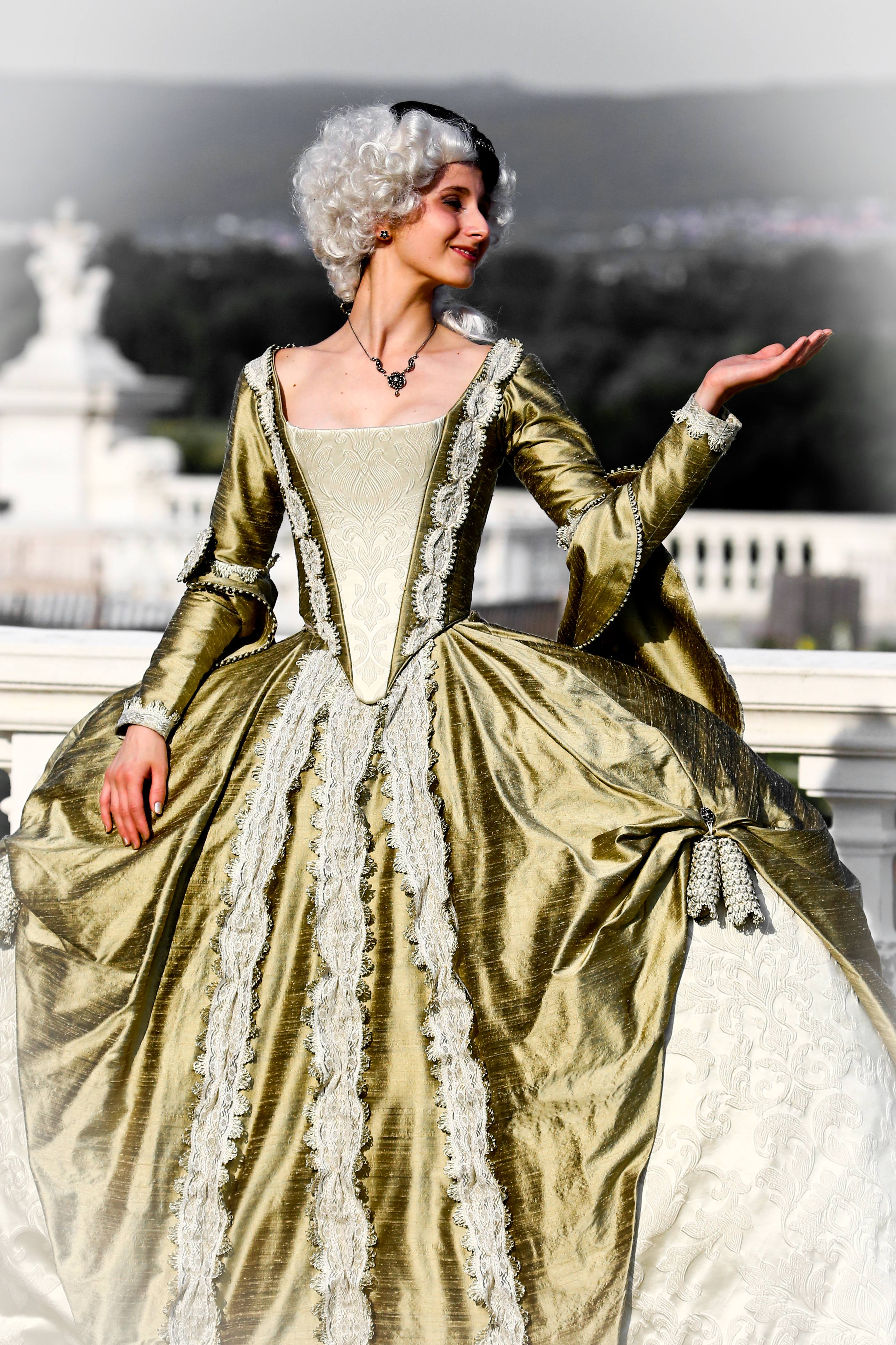 Full-length view of the reconstructed gold court gown at Schloss Hof: a robe à la française of gold silk over an ivory damask stomacher, worn with a powdered wig by its maker Katharina Mayrhofer