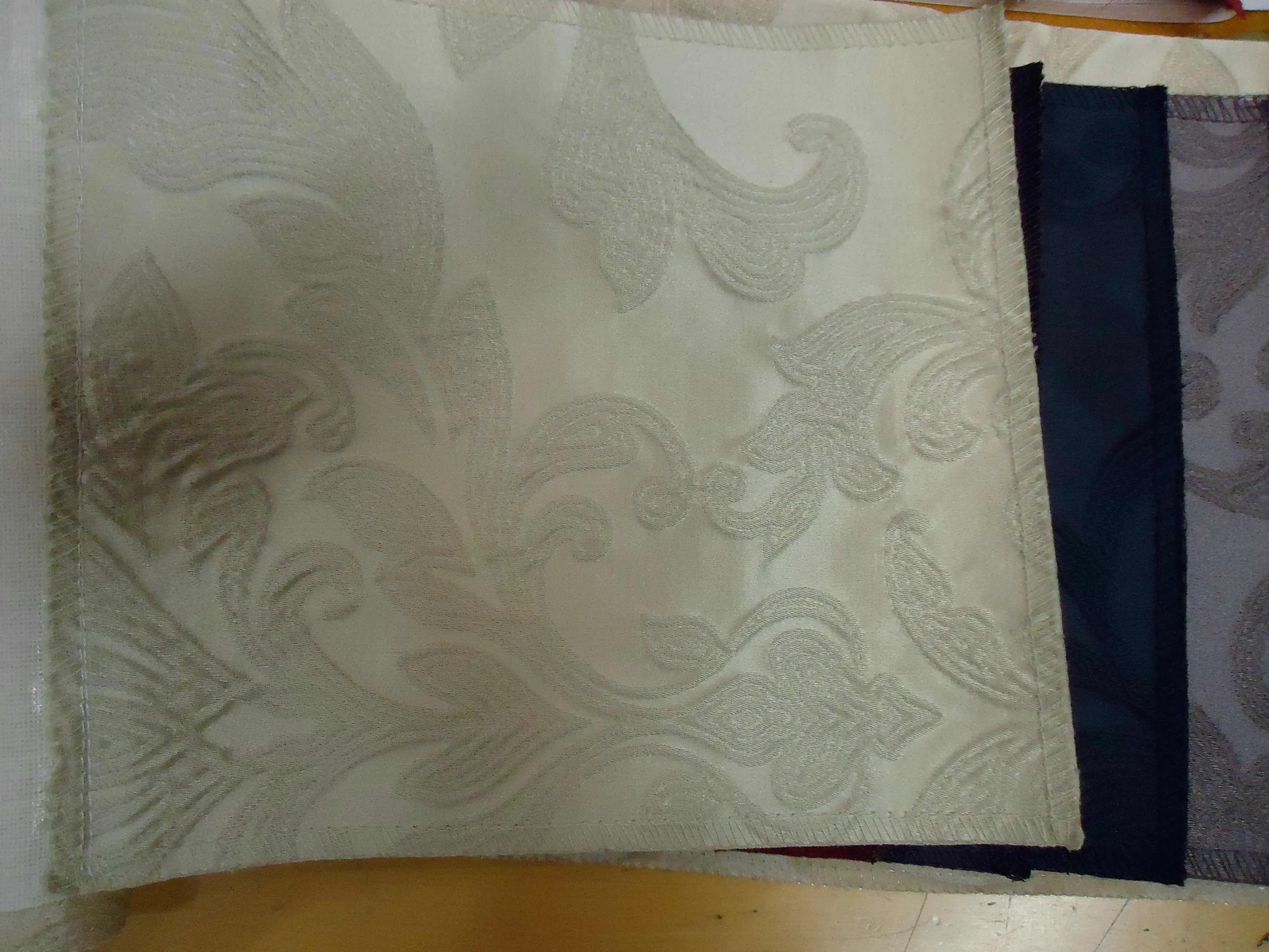 Bolt of ivory silk damask lying open in a fabric sample book