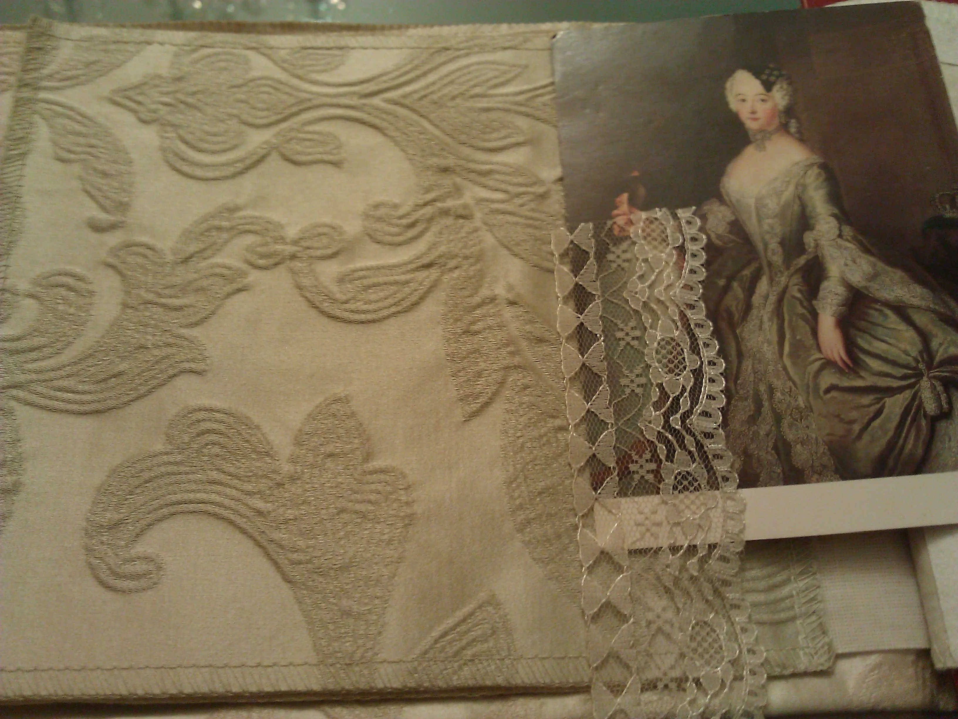 Ivory damask and lace samples arranged beside a printed reproduction of the Pesne portrait