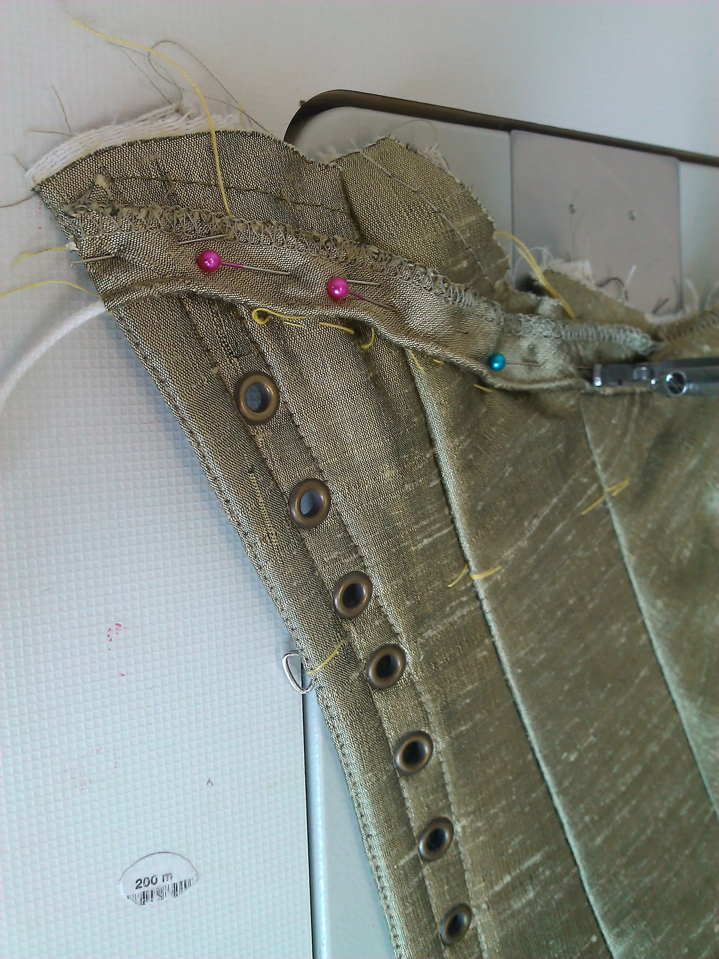 Close view of hand-worked eyelets along the silk-covered edge of the stays