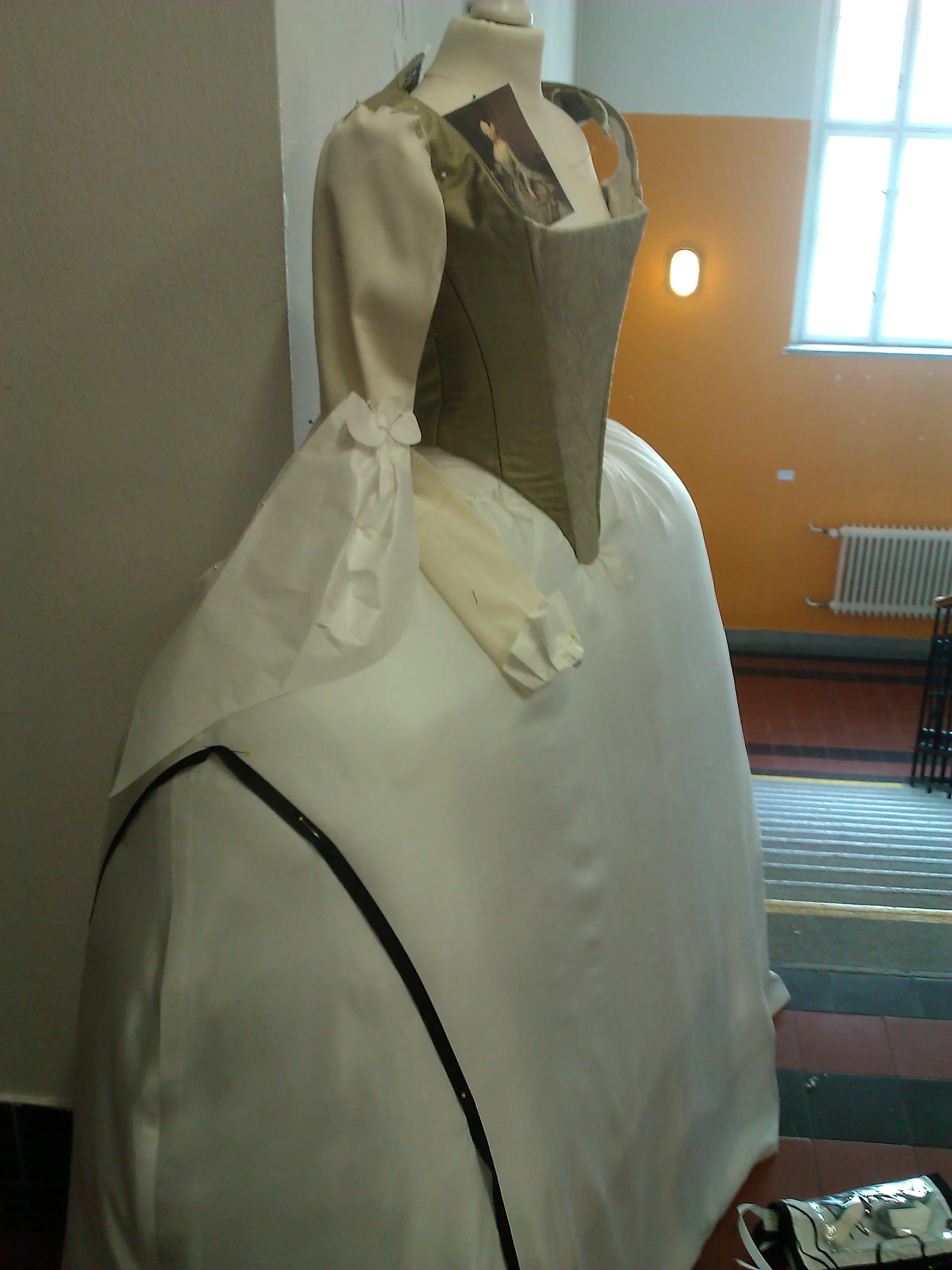 The finished ivory stays on a dress form with a small Pesne reference card tucked into the front