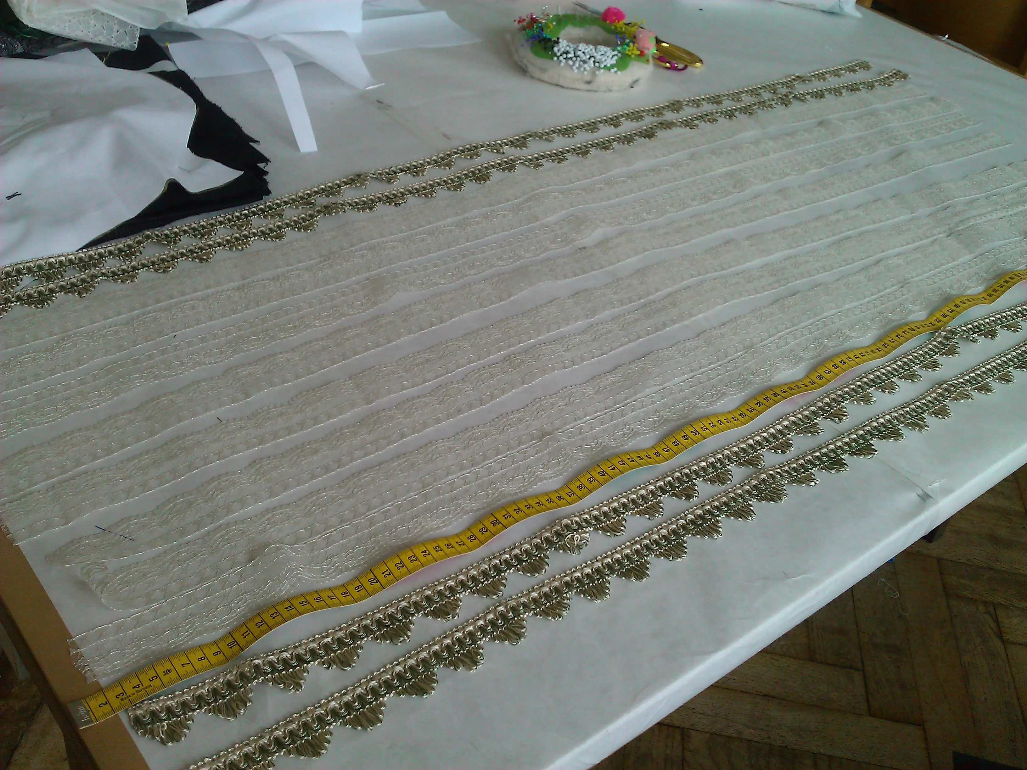 Pleated petticoat borders edged with gold braid lying on the cutting table