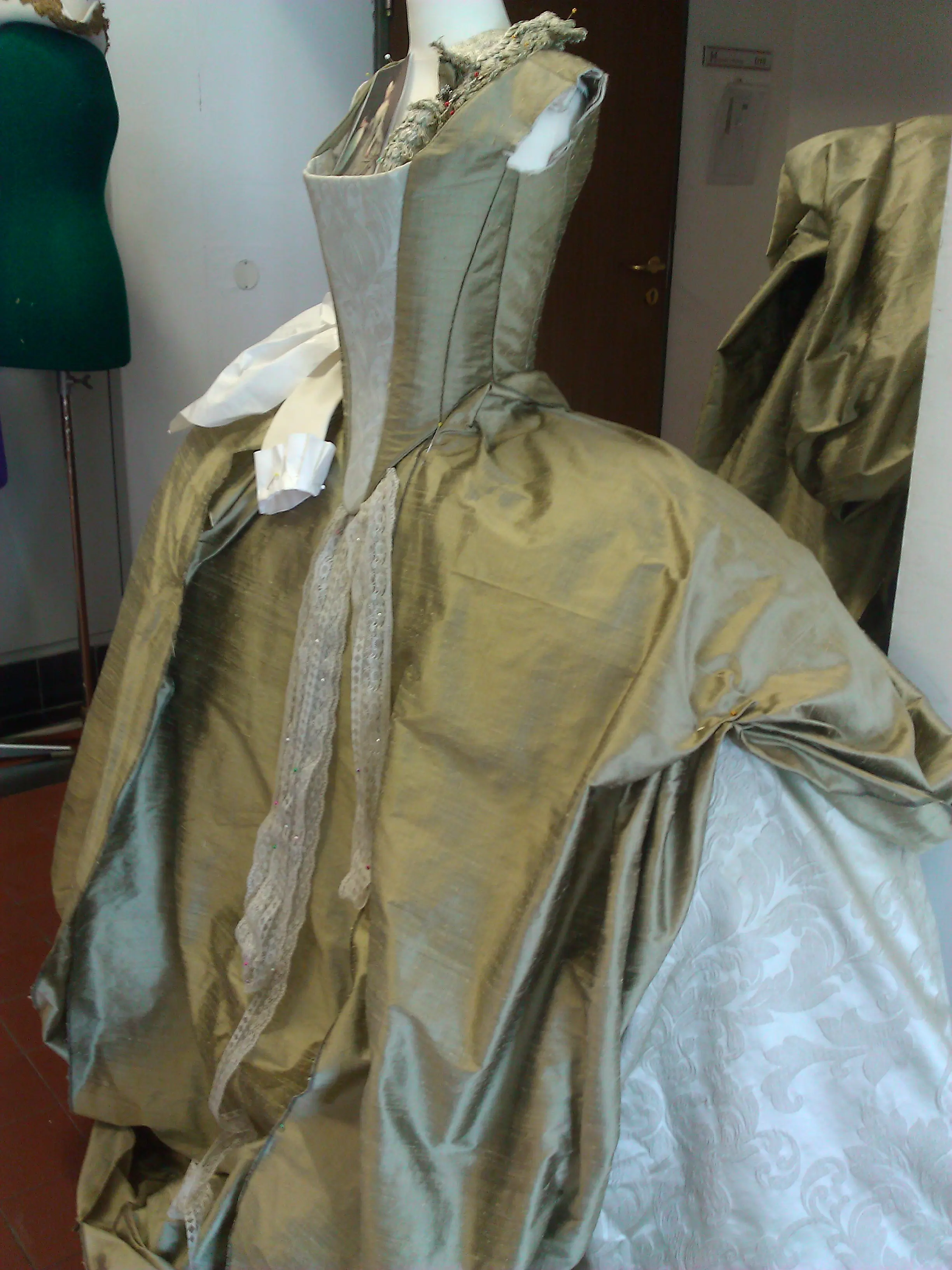 Gold silk bodice and sleeve pinned on a dress form