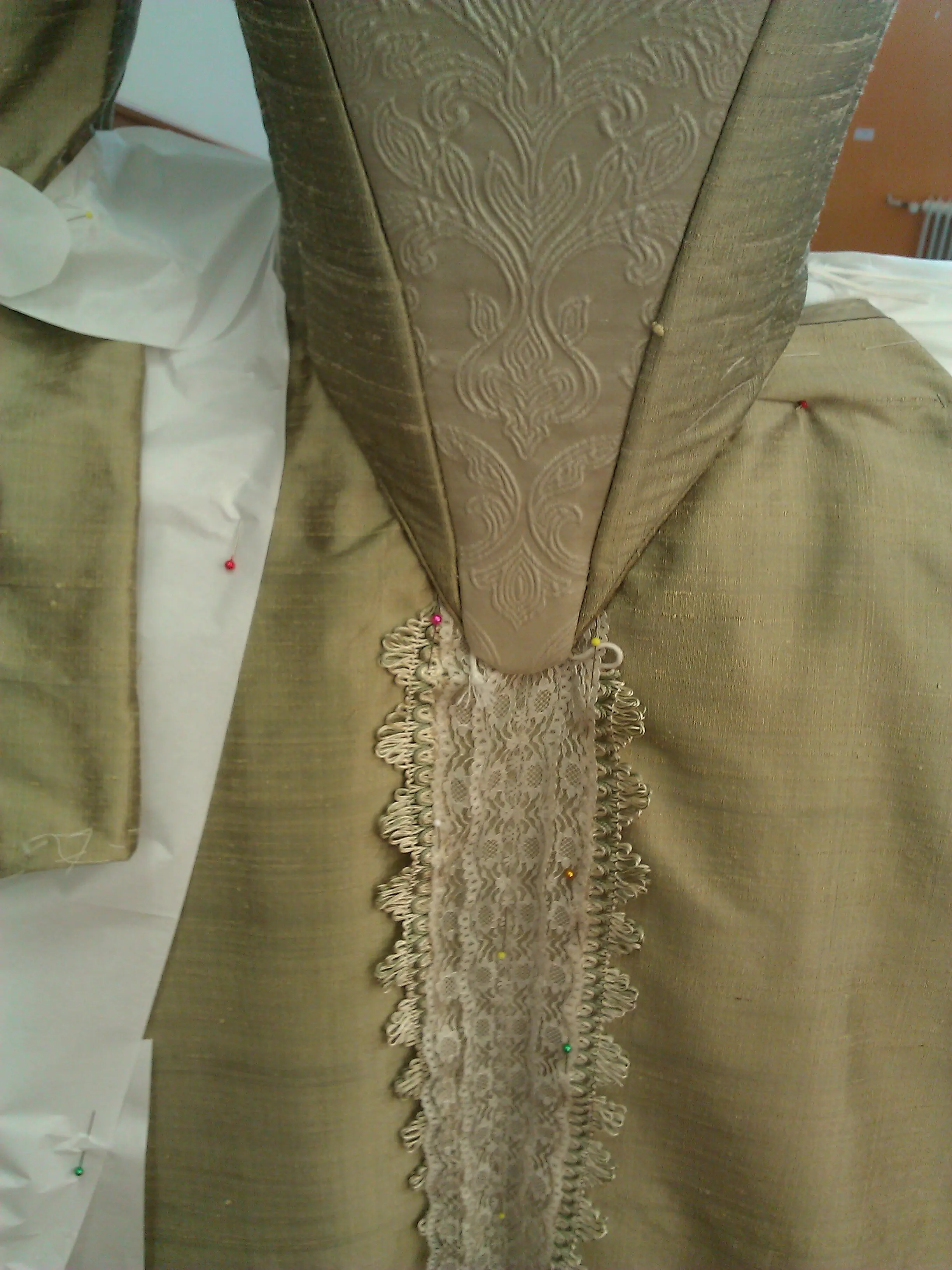 The pointed, laced back of the gold bodice above the skirt