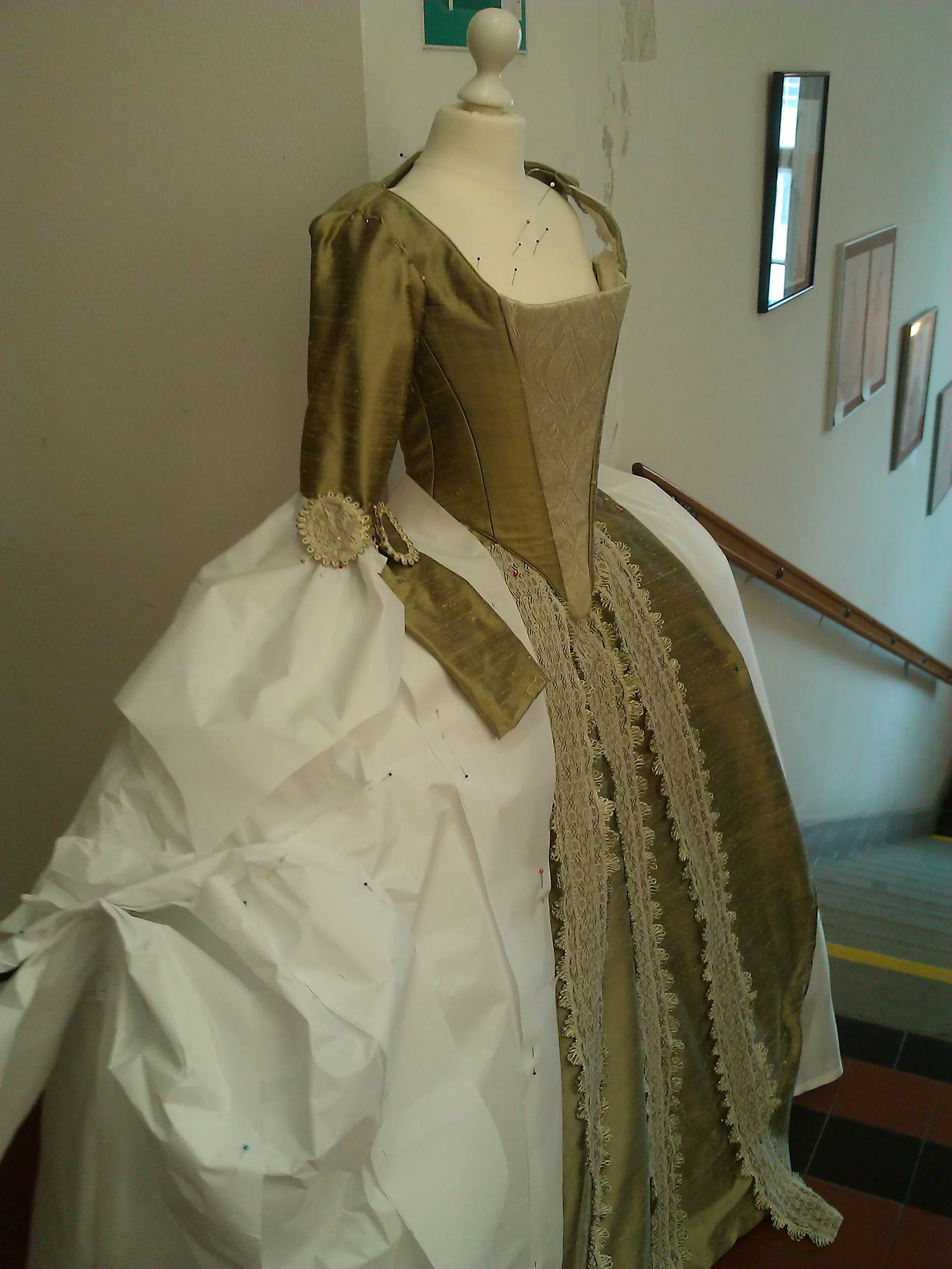 The nearly complete robe à la française on a dress form in the atelier