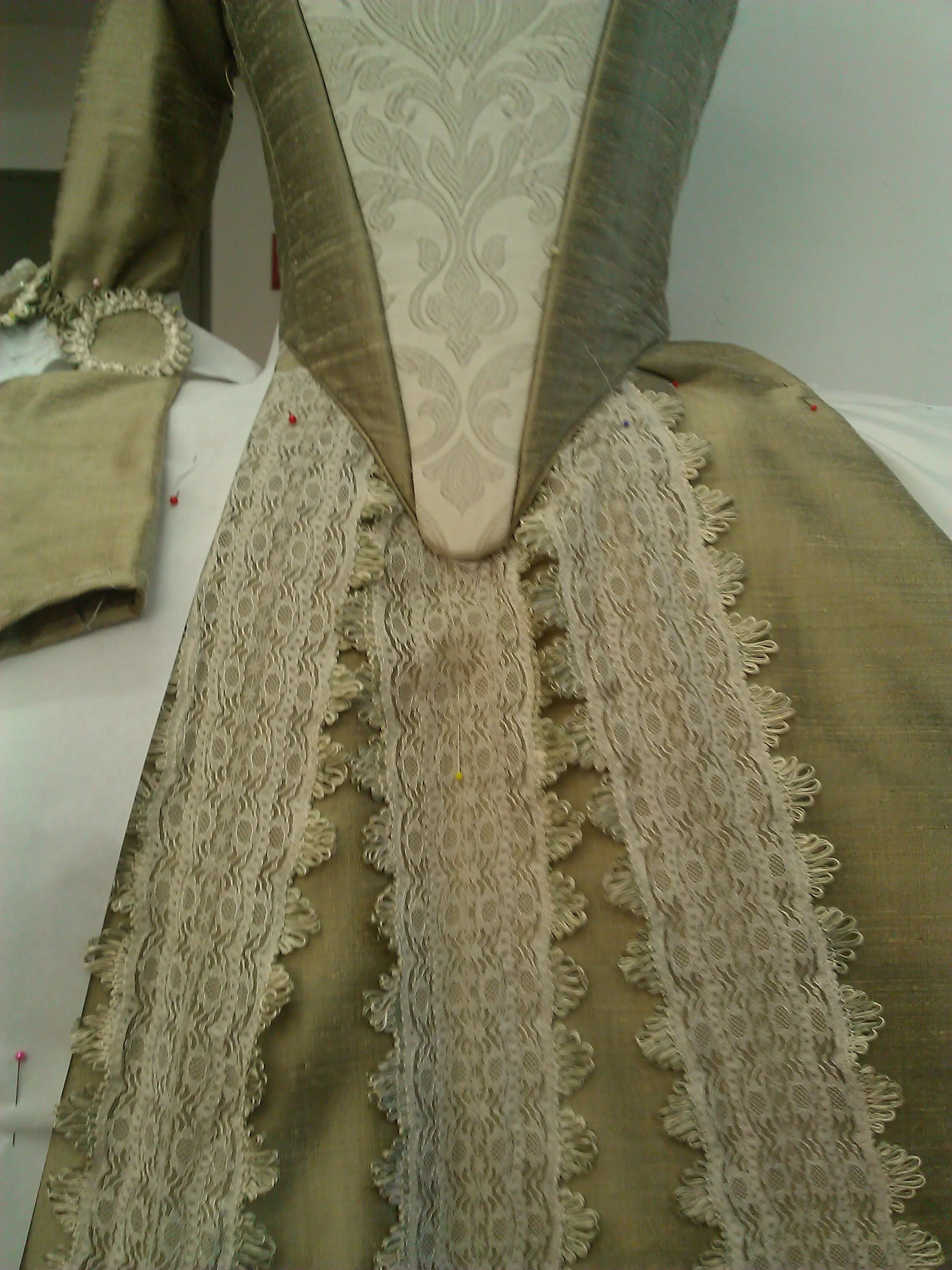Stomacher and vertical lace bands on the front of the gold skirt