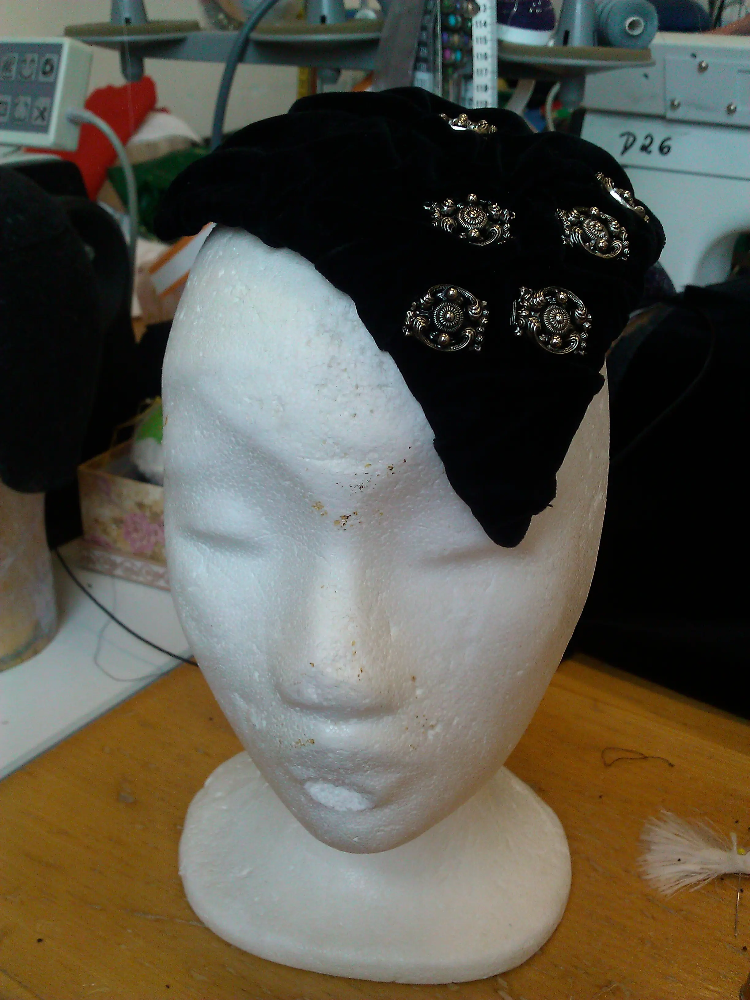 The black velvet hat trimmed with silver rosettes on a head form