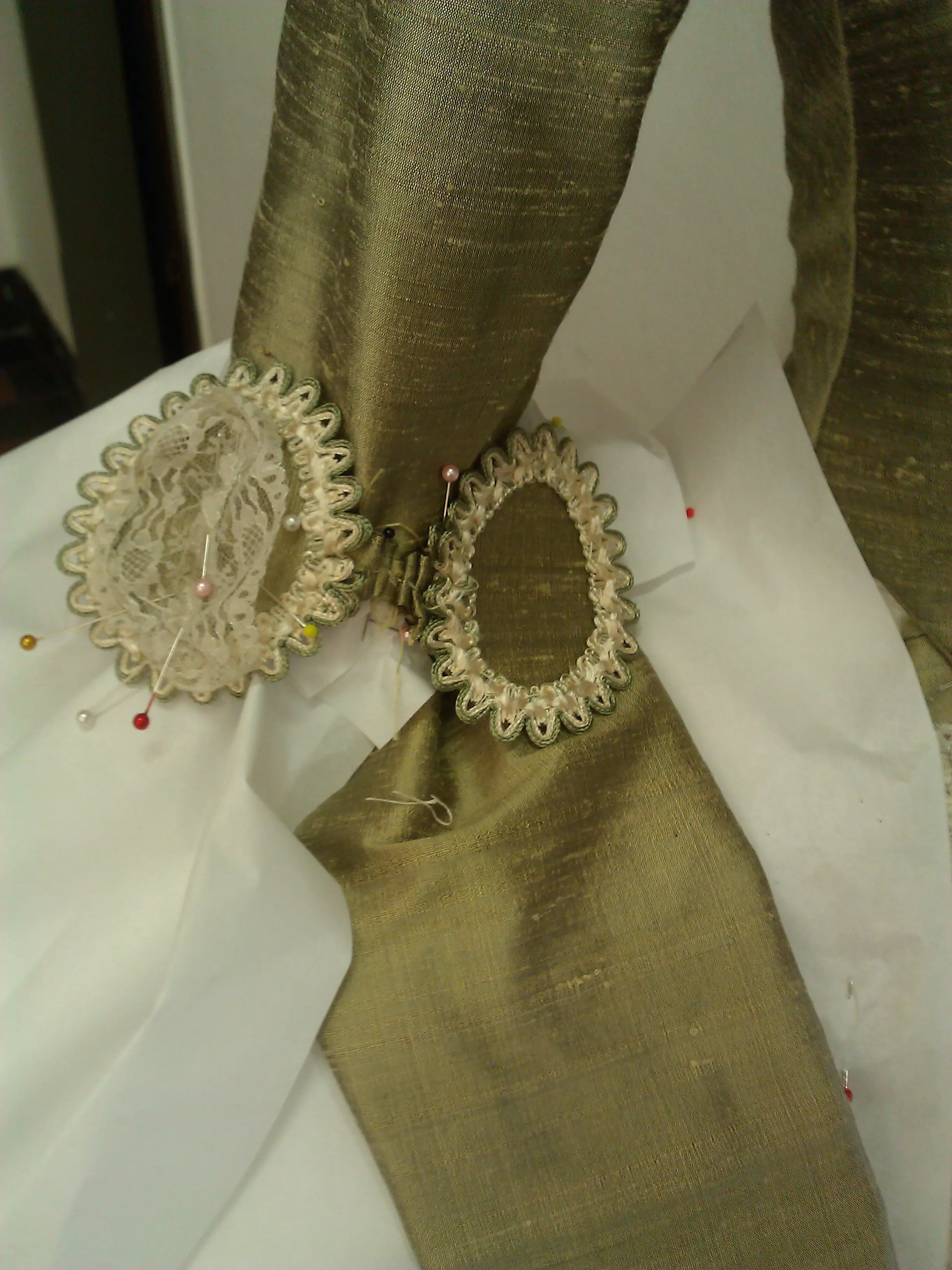 A single silver passementerie rosette resting on the gold silk